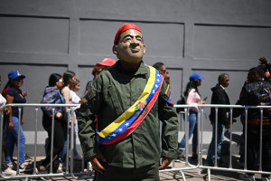 Um homem usando uma m&aacute;scara do falecido presidente Hugo Ch&aacute;vez e vestido com uniforme militar posa durante marcha no Dia Internacional da Juventude, em Caracas.