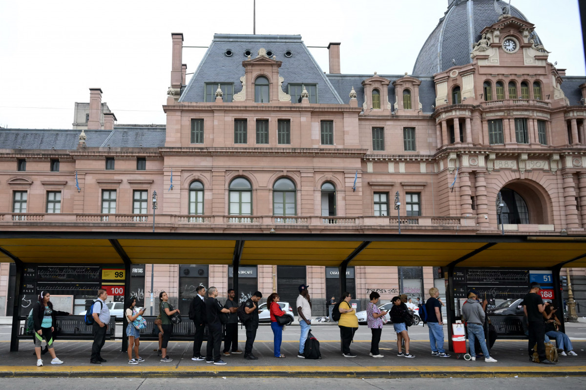 Pessoas aguardam um ônibus em um ponto durante uma greve geral de 24 horas convocada por sindicatos de trabalhadores contra a reforma trabalhista do presidente Javier Milei em Buenos Aires, em 19 de fevereiro de 2026. O governo argentino enfrenta, em 19 de fevereiro, a quarta greve geral de sua administração, no mesmo dia em que a Câmara dos Deputados debaterá uma controversa reforma trabalhista defendida pelo presidente ultraliberal Javier Milei, que já havia sido aprovada pelo Senado na semana passada. (Foto de Luis ROBAYO / AFP)/ AFP