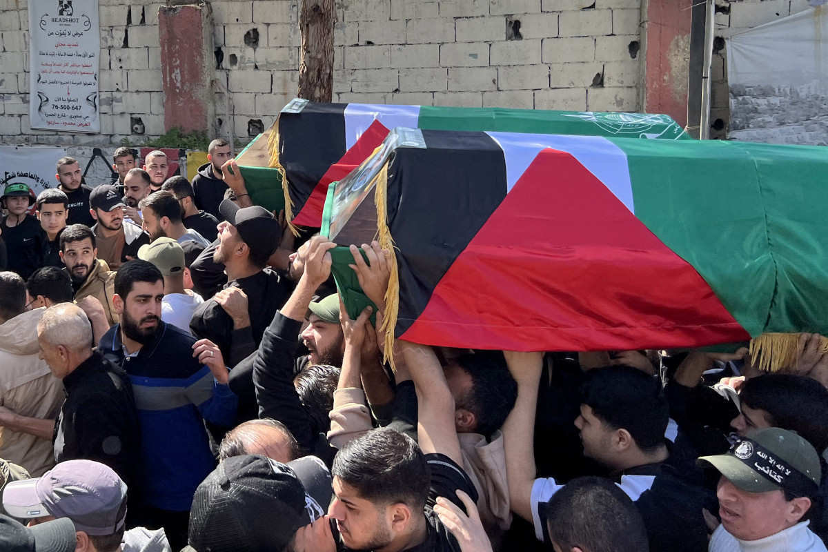Enlutados carregam os caixões de duas pessoas envoltos na bandeira palestina/Foto: Mahmoud ZAYYAT / AFP