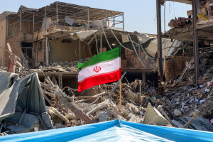 Uma bandeira iraniana colocada em meio aos escombros e destro&ccedil;os ao lado de um pr&eacute;dio residencial destru&iacute;do perto da Pra&ccedil;a Ferdowsi, em Teer&atilde;