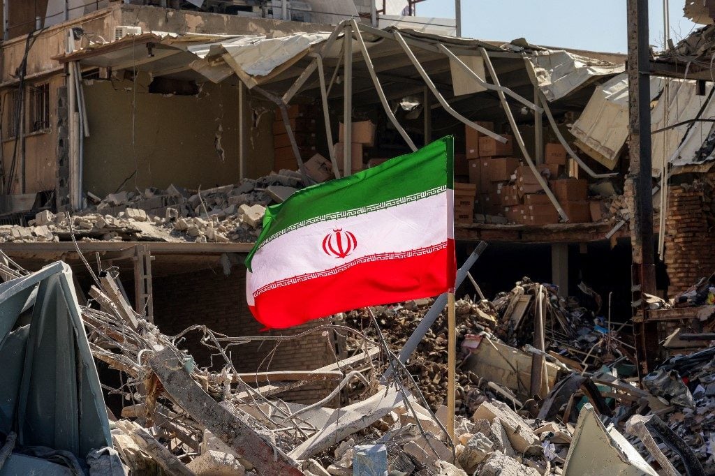 Bandeira iraniana em meio aos escombros de prédio residencial destruído em Teerã/Atta Kenare/AFP