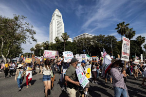 Manifestantes seguram cartazes enquanto marcham em frente &agrave; Prefeitura durante o dia nacional de protesto "No Kings" em Los Angeles
