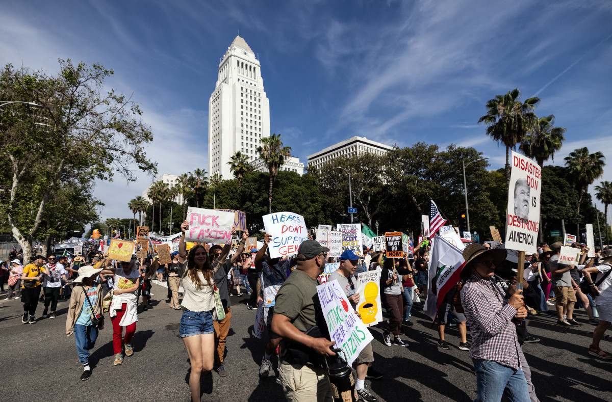 Manifestantes seguram cartazes enquanto marcham em frente à Prefeitura durante o dia nacional de protesto 