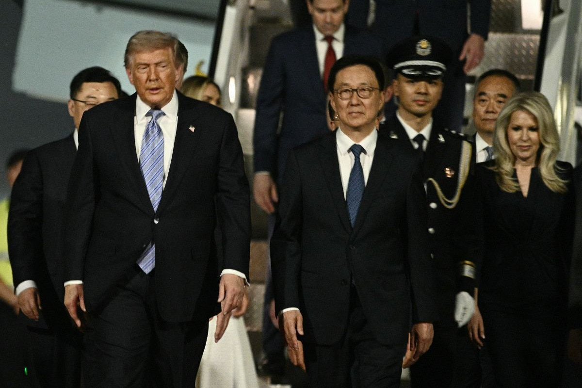 O presidente dos EUA, Donald Trump, desembarca do Air Force One acompanhado pela chefe de protocolo da Casa Branca, Monica Crowley (à direita), e escoltado pelo vice-presidente da China, Han Zheng, ao chegar ao Aeroporto Internacional de Pequim/Brendan SMIALOWSKI/AFP