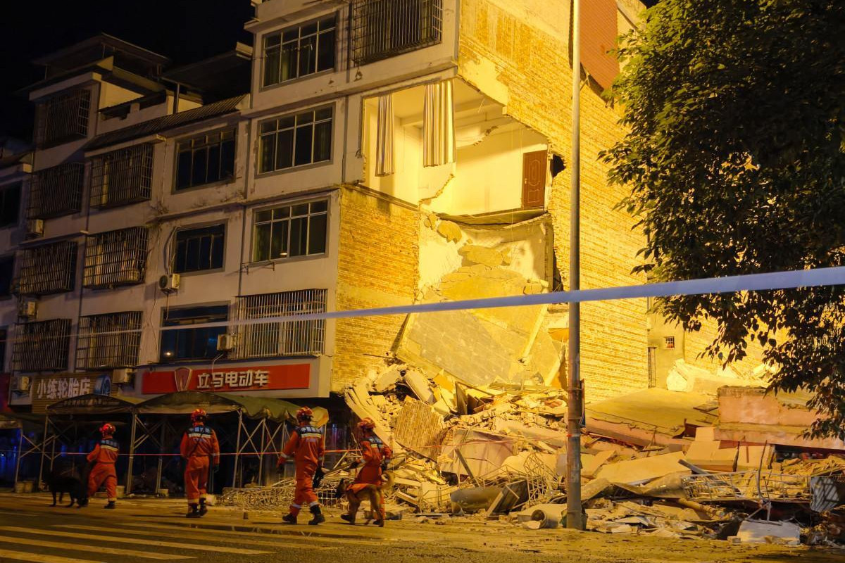 Equipes de resgate caminham ao lado de um prédio que desabou após um terremoto em Liuzhou, na região de Guangxi, no sul da China/CNS/AFP