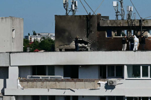 Policiais e peritos forenses examinam o local do impacto ap&oacute;s um drone russo atingir um pr&eacute;dio de apartamentos em Galati, no leste da Rom&ecirc;nia