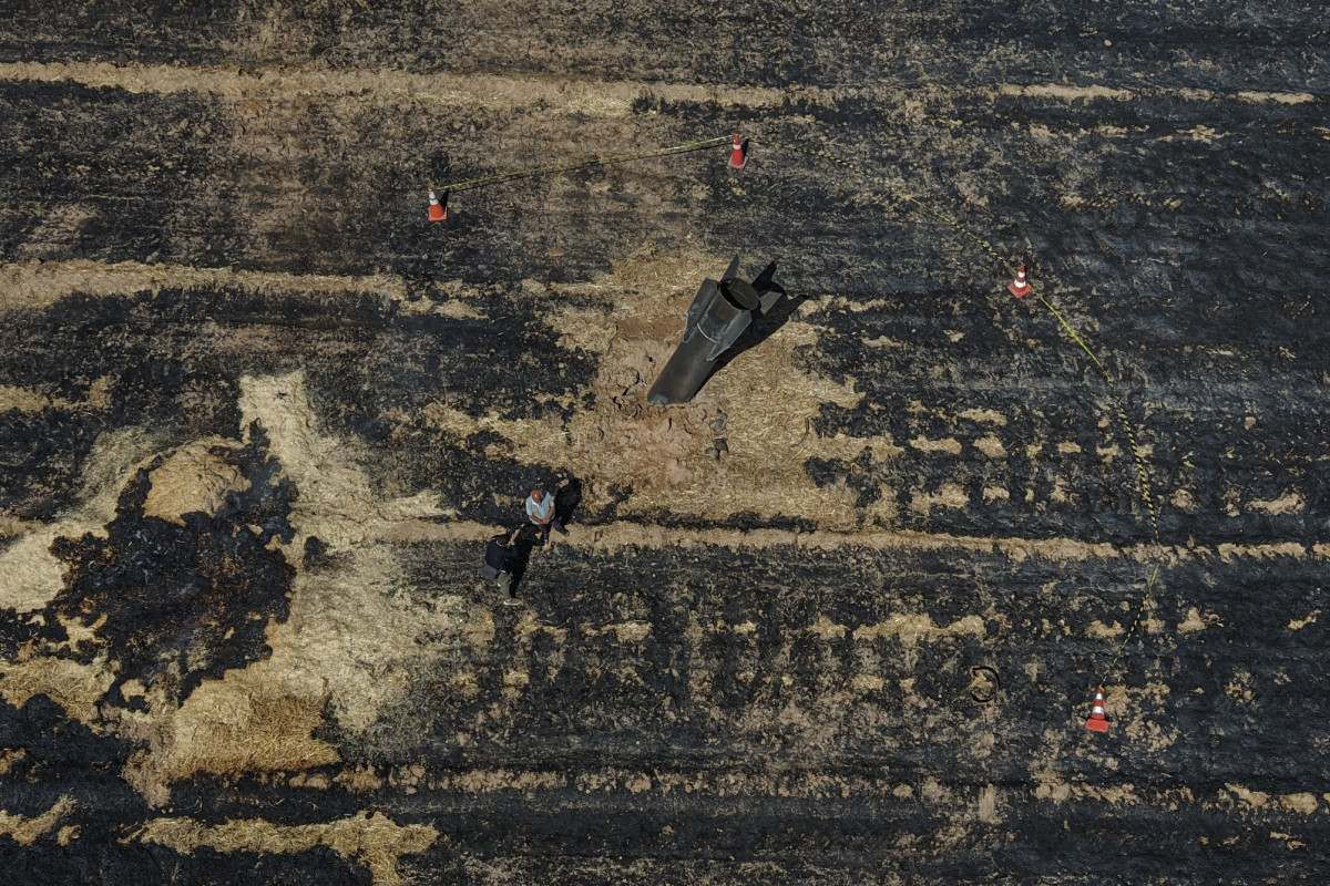 Agricultores sírios ao lado de um míssil iraniano que caiu em uma área agrícola na região de Najha, nos arredores da capital síria, após ser interceptado pelos sistemas de defesa aérea israelenses em 8 de junho de 2026/BAKR ALKASEM/AFP