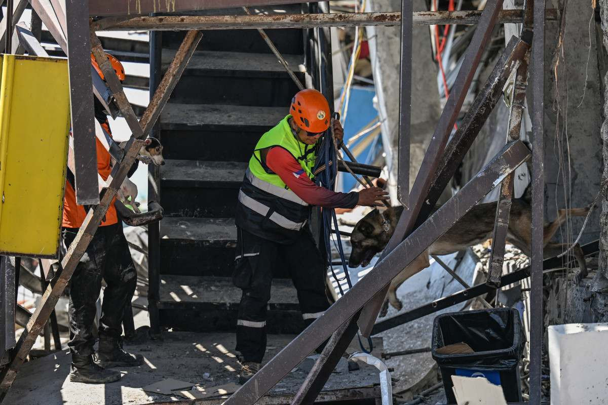 Equipes de resgate e cães farejadores realizam operações de busca e salvamento no prédio que desabou após um terremoto de magnitude 7,8 na cidade de General Santos/JAM STA ROSA/AFP