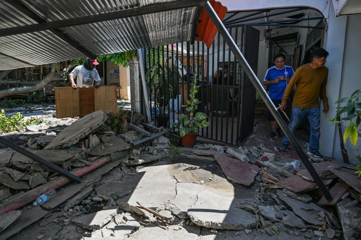 Moradores limpam suas casas danificadas após um terremoto de magnitude 7,8 em General Santos City, em 9 de junho de 2026/JAM STA ROSA/AFP