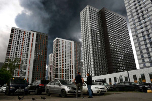 Homens interagem em uma &aacute;rea residencial tomada por fuma&ccedil;a preta em Moscou, em 18 de junho de 2026. 