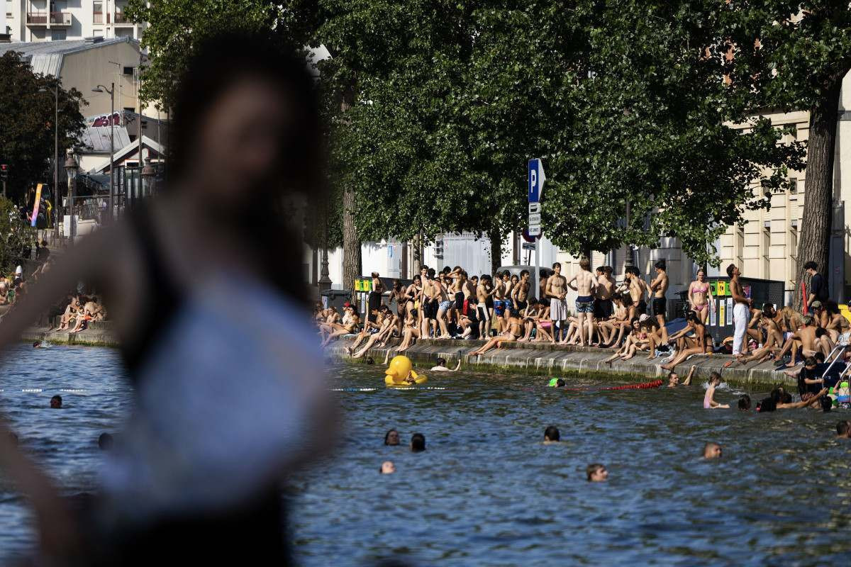  Swimmers sunbath on the banks of the Canal Saint-Martin as France experiences a heatwave, in Paris on June 22, 2026. Due to the ongoing heatwave sweeping across France - the Bassin des Recollets - a portion of the Canal Saint-Martin in the French capital has been opened for swimming from June 17. (Photo by JOEL SAGET / AFP)
      Caption/ AFP