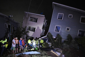 Moradores e equipes de emerg&ecirc;ncia permanecem pr&oacute;ximos a pr&eacute;dios danificados ap&oacute;s um terremoto em Catia La Mar, a cerca de 30 km a noroeste de Caracas, na madrugada de 25 de junho de 2026