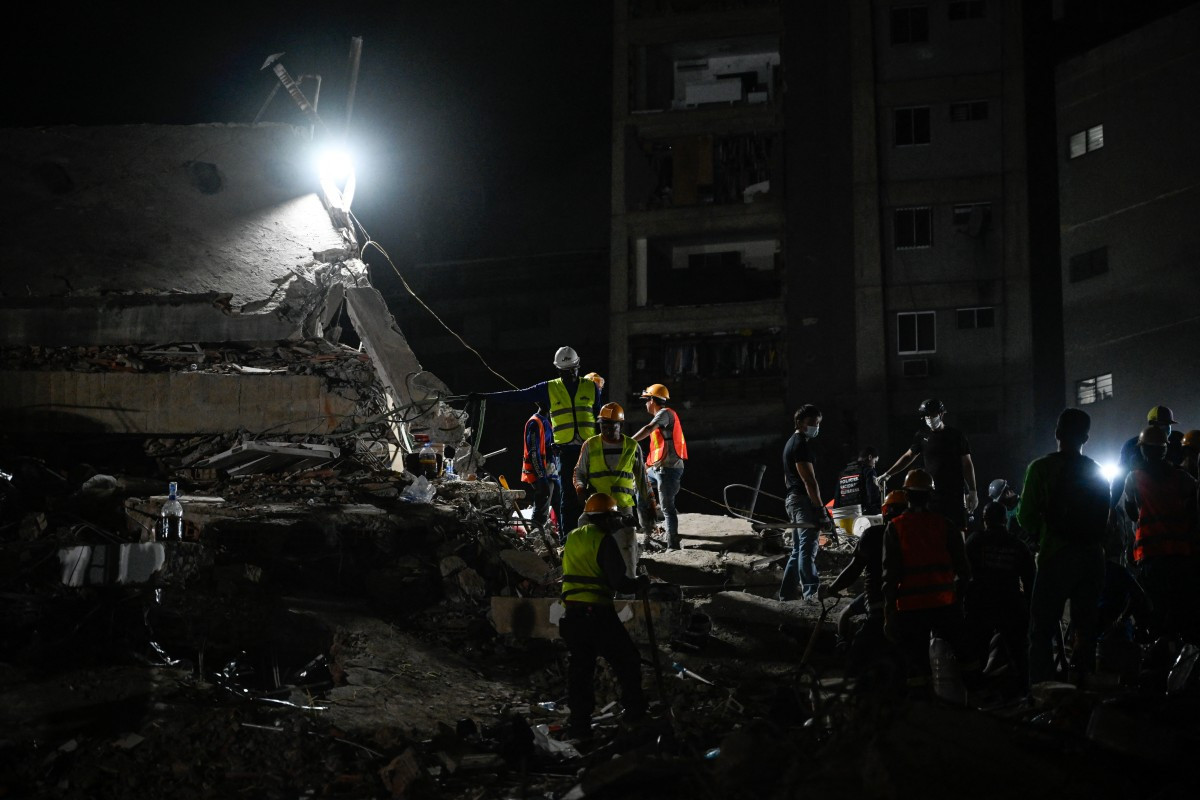 Equipes de resgate e voluntários vasculham os escombros de um prédio que desabou após dois terremotos em Caracas/MARYORIN MENDEZ/AFP