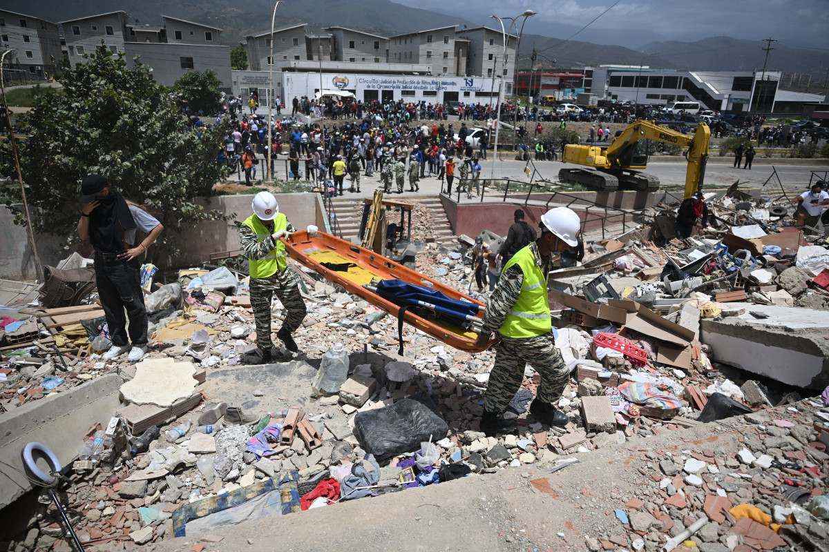 Integrantes da Polícia Nacional Bolivariana carregam uma maca sobre os escombros de prédios danificados em Catia La Mar, na Venezuela/Federico Parra/AFP
