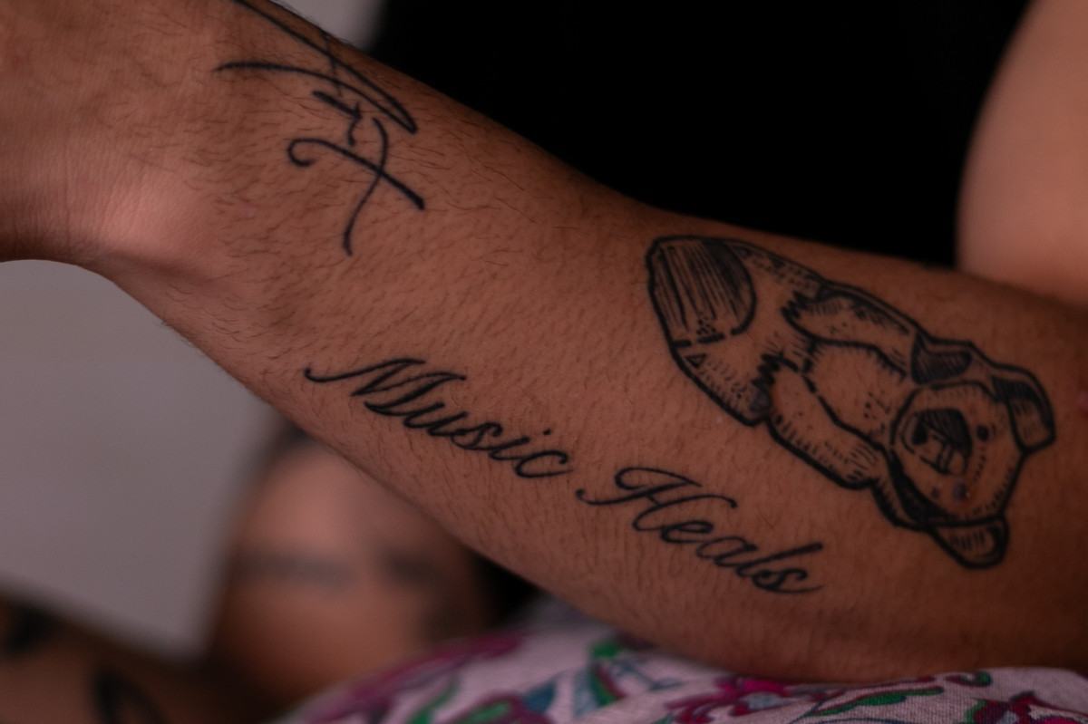 Jovem tem uma tatuagem no antebraço que diz "Música Cura" em inglês (Foto: Rafael Vieira/DP Foto)