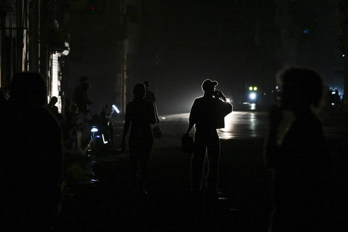 Pessoas caminham por uma rua durante um apagão nacional em Havana/YAMIL LAGE/AFP
