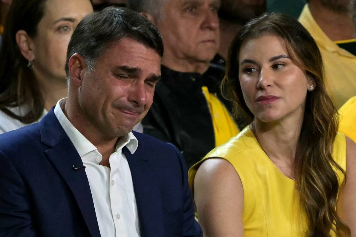 Flávio Bolsonaro chora ao lado de sua esposa, Fernanda, durante a convenção do PL/Nelson Almeida/AFP