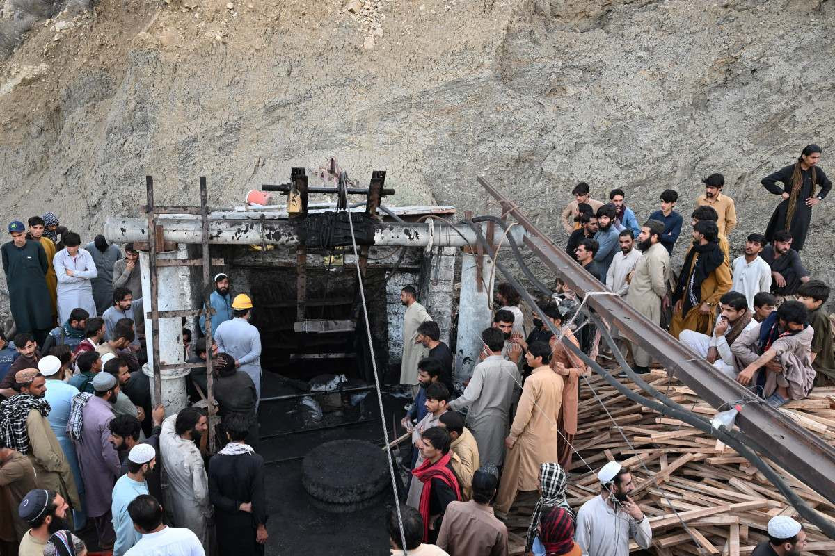 Trabalhadores, familiares e equipes de resgate reúnem-se na entrada da mina de carvão após o seu desabamento/BANARAS KHAN / AFP