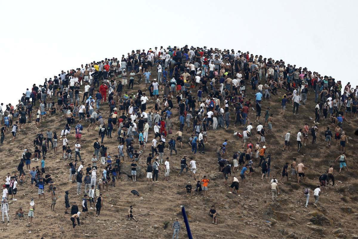Pessoas se reúnem no topo de uma colina próxima ao local de confrontos perto de Fnideq, na fronteira entre o Marrocos e a Espanha/ABDEL MAJID BZIOUAT/AFP
