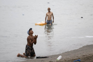 Um migrante faz gestos na praia, perto da barreira fronteiri&ccedil;a com o Marrocos, para tentar entrar no enclave espanhol de Ceuta, no norte da &Aacute;frica