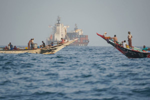 Pessoas navegam pr&oacute;ximo a porta-cont&ecirc;ineres ancorados perto do Estreito de Bab el-Mandeb, na costa do I&ecirc;men, no Golfo de Aden