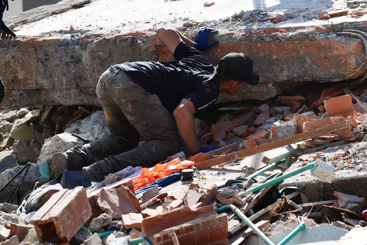 Homem procura por sobreviventes entre os escombros de um prédio que desabou após um terremoto em Pereira, na Colômbia/Jaime Saldarriaga/AFP
