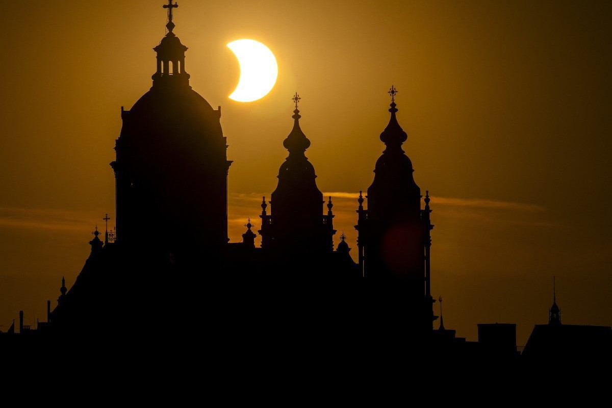 Lua passa sobre o horizonte solar atrás da Basílica de São Nicolau, em eclipse solar parcial em Amsterdã/Remko de Waal/ANP/AFP