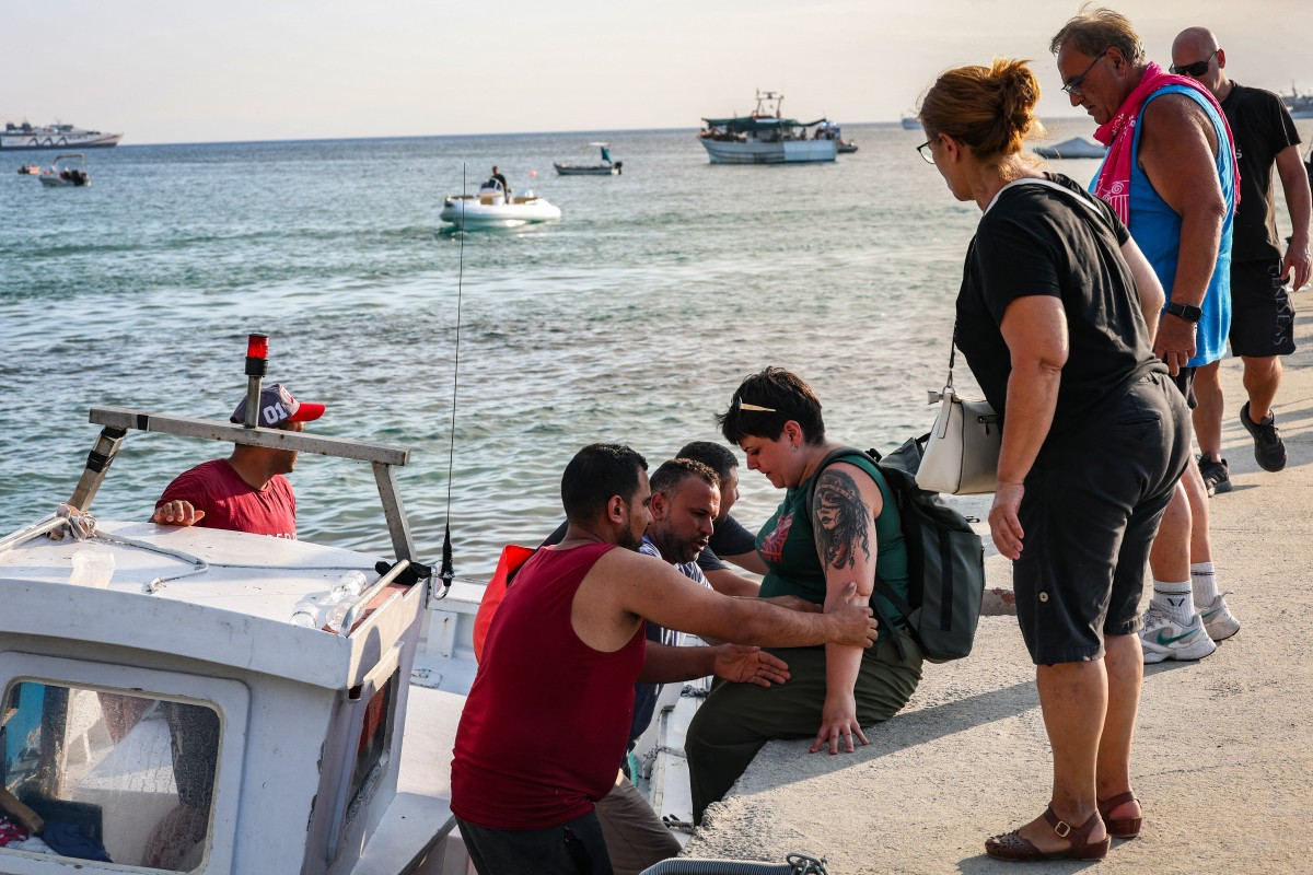 Pessoas são evacuadas em pequenas embarcações durante um incêndio florestal perto do vilarejo de Siviri, no norte da Grécia/Vasilis Ververidis/AFP