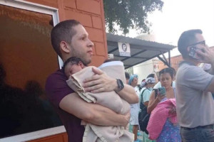 O m&eacute;dico German Andres Somoyar carrega rec&eacute;m-nascidos removidos durante terremoto 