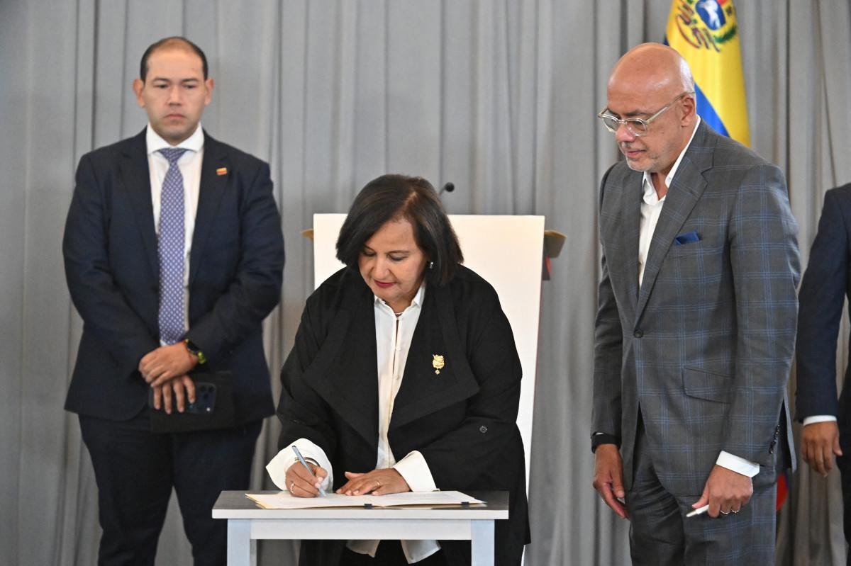 A representante da oposição venezuelana Dinorah Figuera assina um acordo ao lado do presidente da Assembleia Nacional, Jorge Rodríguez (à direita), após uma reunião em Caracas/JUAN BARRETO/AFP