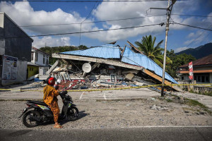 Uma motocicleta para ao lado de um pr&eacute;dio desabado ap&oacute;s um terremoto de magnitude 7,7 em Borong, Manggarai Oriental, Nusa Tenggara Oriental