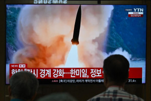 Pessoas observam uma tela de televis&atilde;o que exibe um notici&aacute;rio com imagens de arquivo de um teste de m&iacute;ssil norte-coreano