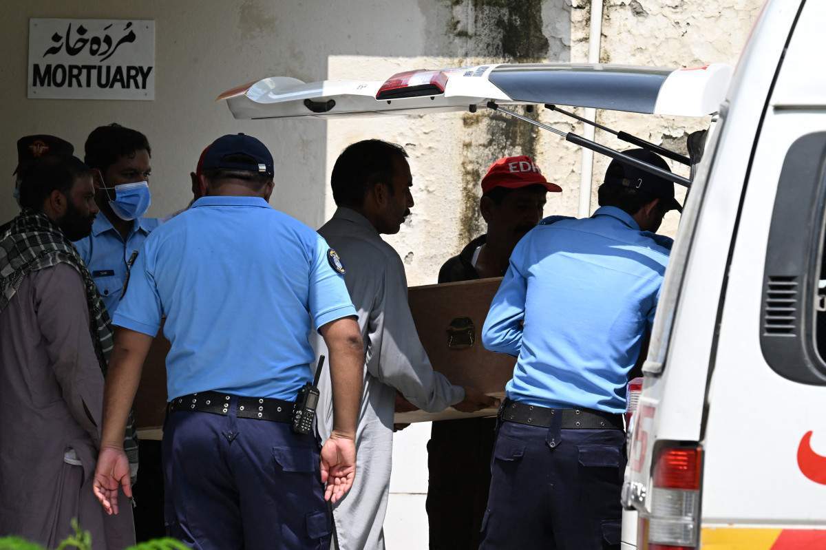 Policiais transferindo um caixão contendo uma criança vítima do incêndio/AAMIR QURESHI / AFP