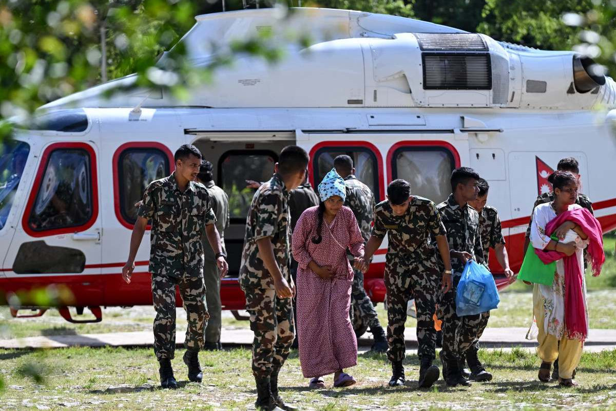 Equipes de resgate socorrendo uma mulher vítima das inundações que aconteceu entre o Nepal e Tibete/ARUN SANKAR / AFP