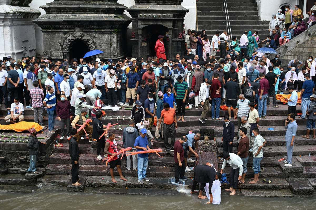 Familiares carregam efígies feitas de grama Kush para cremação, seguindo os ritos hindus nepaleses, durante funerais simbólicos realizados para vítimas de enchentes que ainda constam como desaparecidas/PRAKASH MATHEMA/AFP