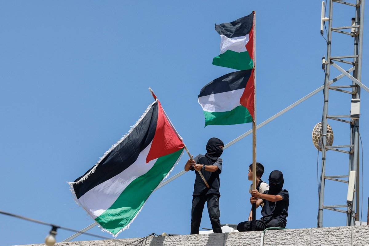 Meninos acenam bandeiras palestinas durante funeral dos jovens Khalil Rasem, de 16 anos, e Omar Mohammad Naji al-Nassan, de 19/Zain Jaafar/AFP