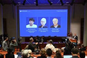 Abdel El Manira, professor de neuroci&ecirc;ncia do Instituto Karolinska, fala diante de uma tela que exibe retratos do cientista americano Karl Deisseroth e dos cientistas alem&atilde;es Peter Hegemann e Georg Nagel durante o an&uacute;ncio dos vencedores do Pr&ecirc;mio Nobel de Fisiologia ou Medicina de 2026