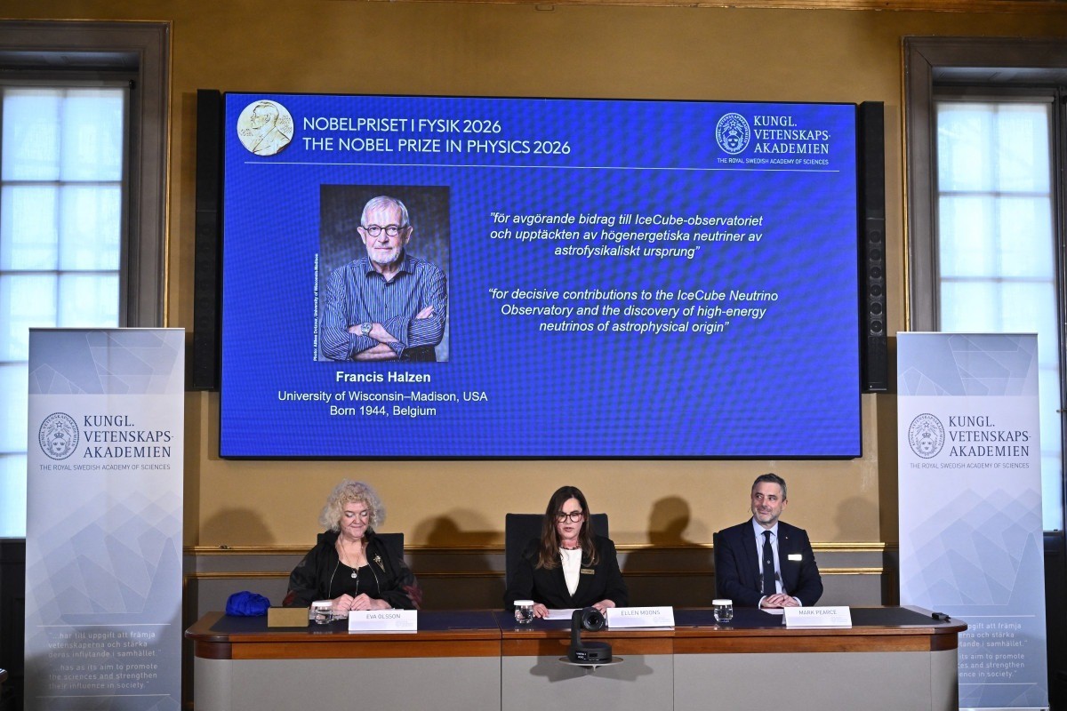 Eva Olsson, Ellen Moons e Mark Pearce sentados diante de uma tela que exibe Francis Halzen como o ganhador do Prêmio Nobel de Física de 2026, durante uma coletiva de imprensa/CHRISTINE OLSSON/TT NEWS AGENCY/AFP