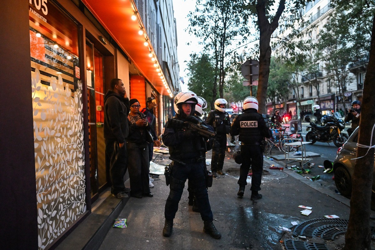 Policiais em frente a uma loja saqueada, após confrontos na Praça da República, no centro de Paris. / AFP