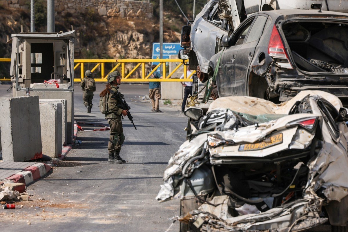 Um soldado israelense conversa com um motorista no posto de controle norte, bloqueado, em Hebron, na Cisjordânia ocupada/Foto: HAZEM BADER/AFP