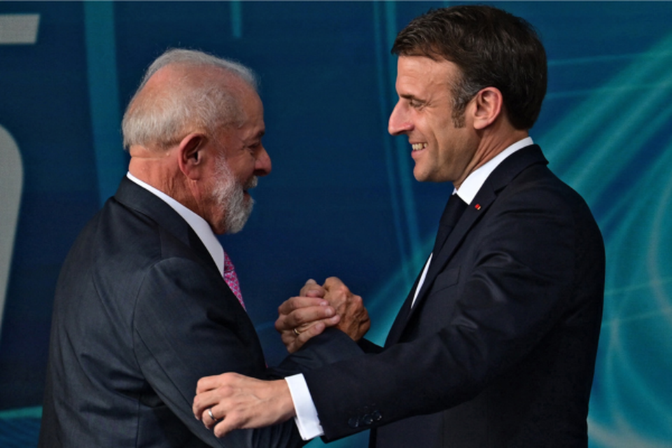 O presidente brasileiro Luiz Incio Lula da Silva (E) e o presidente francs Emmanuel Macron apertam as mos durante o lanamento do submarino Tonelero (Crdito: PABLO PORCIUNCULA / AFP
)