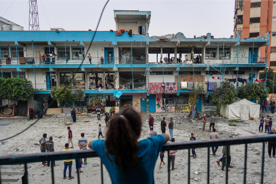 Uma menina palestina observa enquanto outras pessoas verificam uma escola da ONU que abriga pessoas deslocadas que foi atingida durante o bombardeio israelense em Nuseirat, no centro da Faixa de Gaza (Crdito: BASHAR TALEB / AFP)