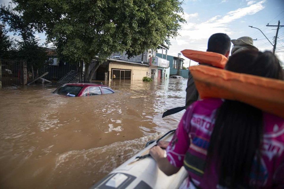 Katiane Mello sai da sua casa inundada em um barco navegando por uma rua em Eldorado do Sul, no Rio Grande do Sul (Crdito: Carlos Fabal / AFP)