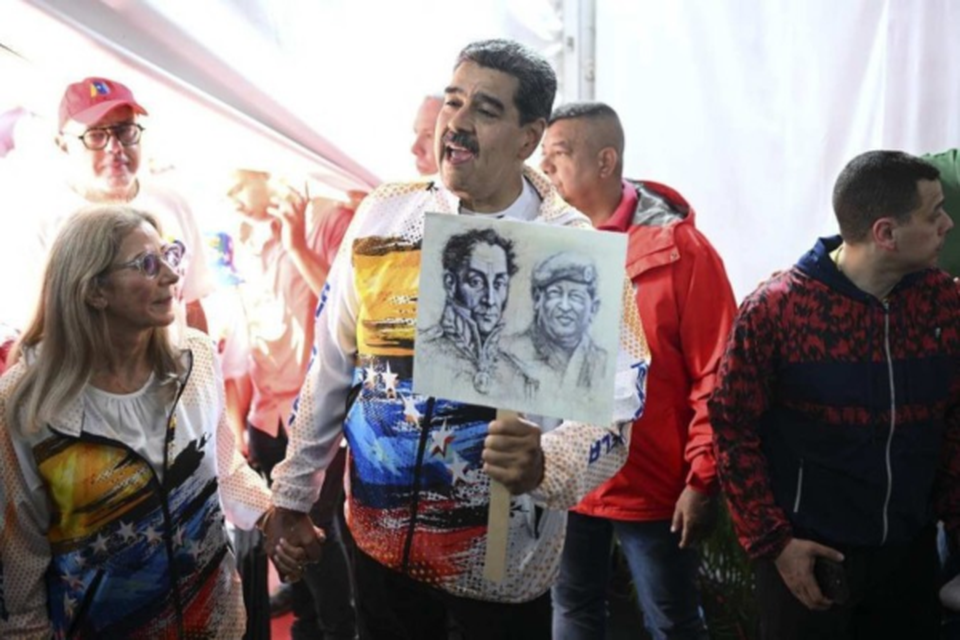 Acompanhado da primeira-dama Cilia Flores, Nicols Maduro exibe imagens de Simn Bolvar e de Hugo Chvez, ao visitar o Conselho Nacional Eleitoral  (Crdito: Federico Parra/AFP)