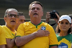
O ex-presidente brasileiro Jair Bolsonaro (C) canta o hino nacional ao lado de sua esposa Michelle Bolsonaro (R) e do pastor Silas Malafaia (L) durante um comício em São Paulo 