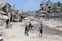 Crianas palestinas andam de bicicleta por uma rua devastada pelo bombardeio israelense na Cidade de Gaza