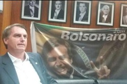 
Bolsonaro em seu gabinete na Câmara, em 2018, tendo ao fundo fotos dos militares presidentes na ditadura: Castello Branco, Costa e Silva, Médici, Geisel e Figueiredo