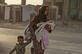 Uma mulher foge com seus filhos em meio a um bombardeio turco na cidade de Ras al-Ain, no nordeste da Sria, na provncia de Hasakeh, ao longo da fronteira com a Turquia, nesta quarta - feira (09). Foto: Delil SOULEIMAN / AFP. - 