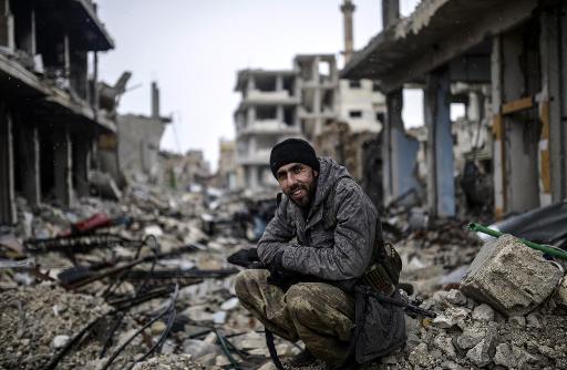 Musa, um curdo de 25 anos,  visto sentado em escombros na cidade sria de Kobane destruda. Foto: AFP BULENT KILIC 