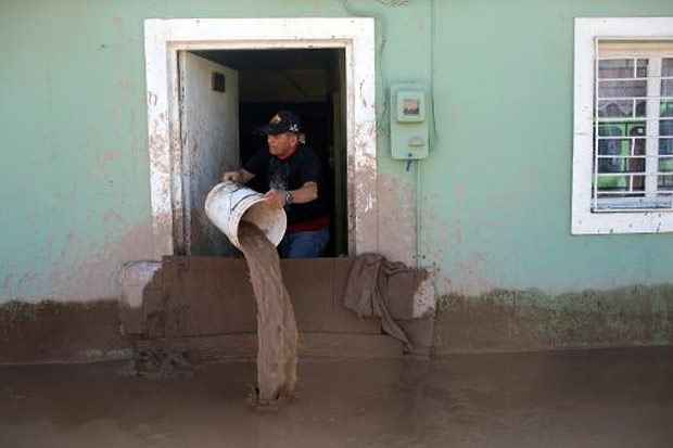 Homem tira gua de casa, atingida por uma enchente, na cidade chilena de Copiap. Foto: Pablo Sanhueza/AFP